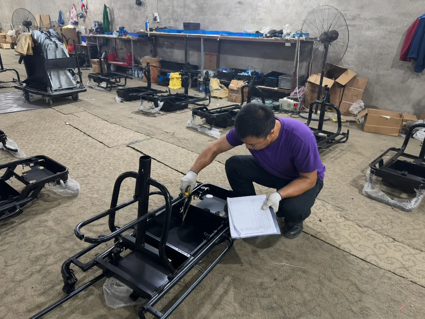 Worker measuring an incoming electric tricycle frame before assembly